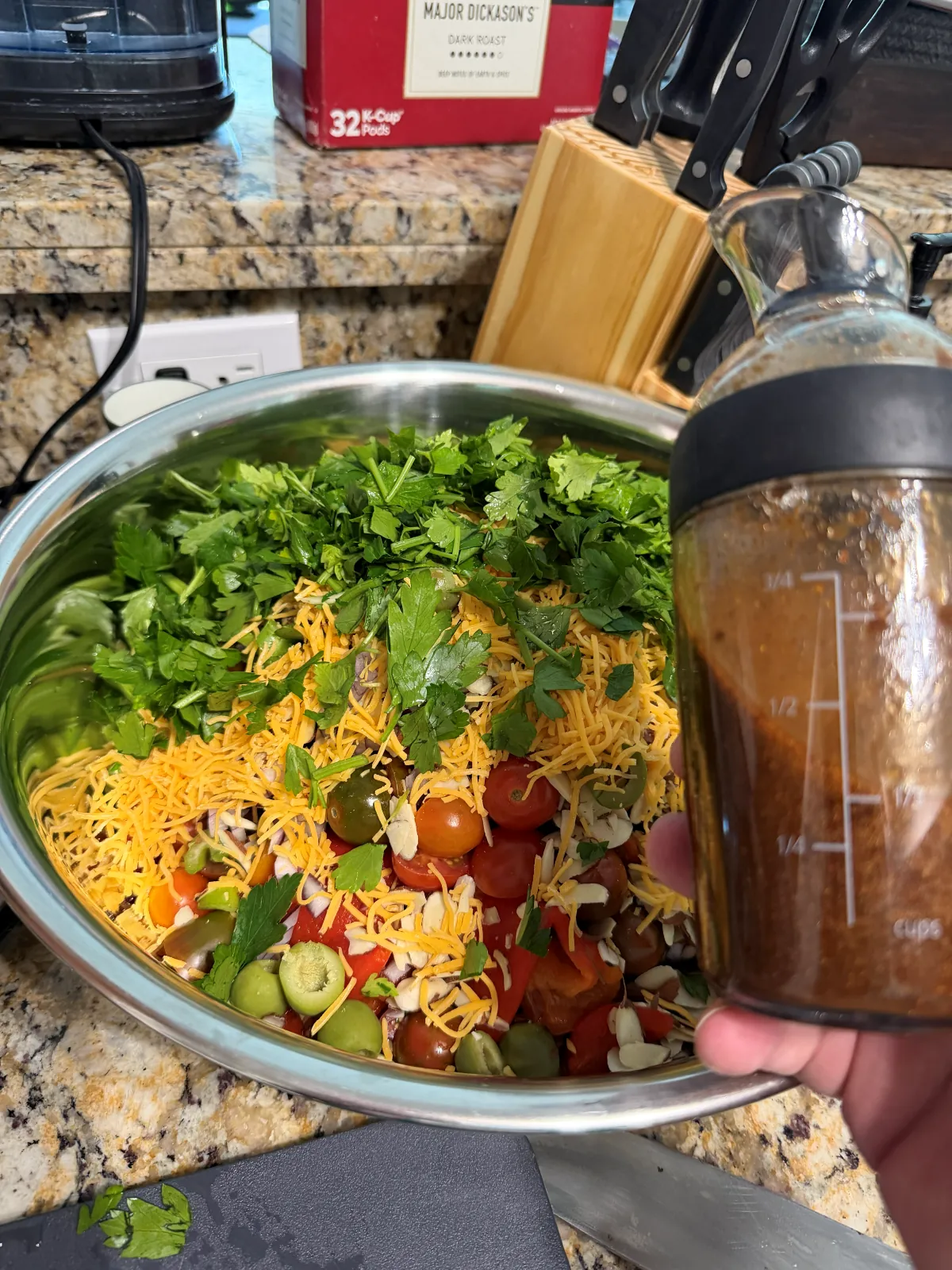 A big steel bowl of black-eyed peas, cherry tomatoes, green olives, cheese and a pile of parsley, with a jar of smoky paprika dressing alongside, before tossing