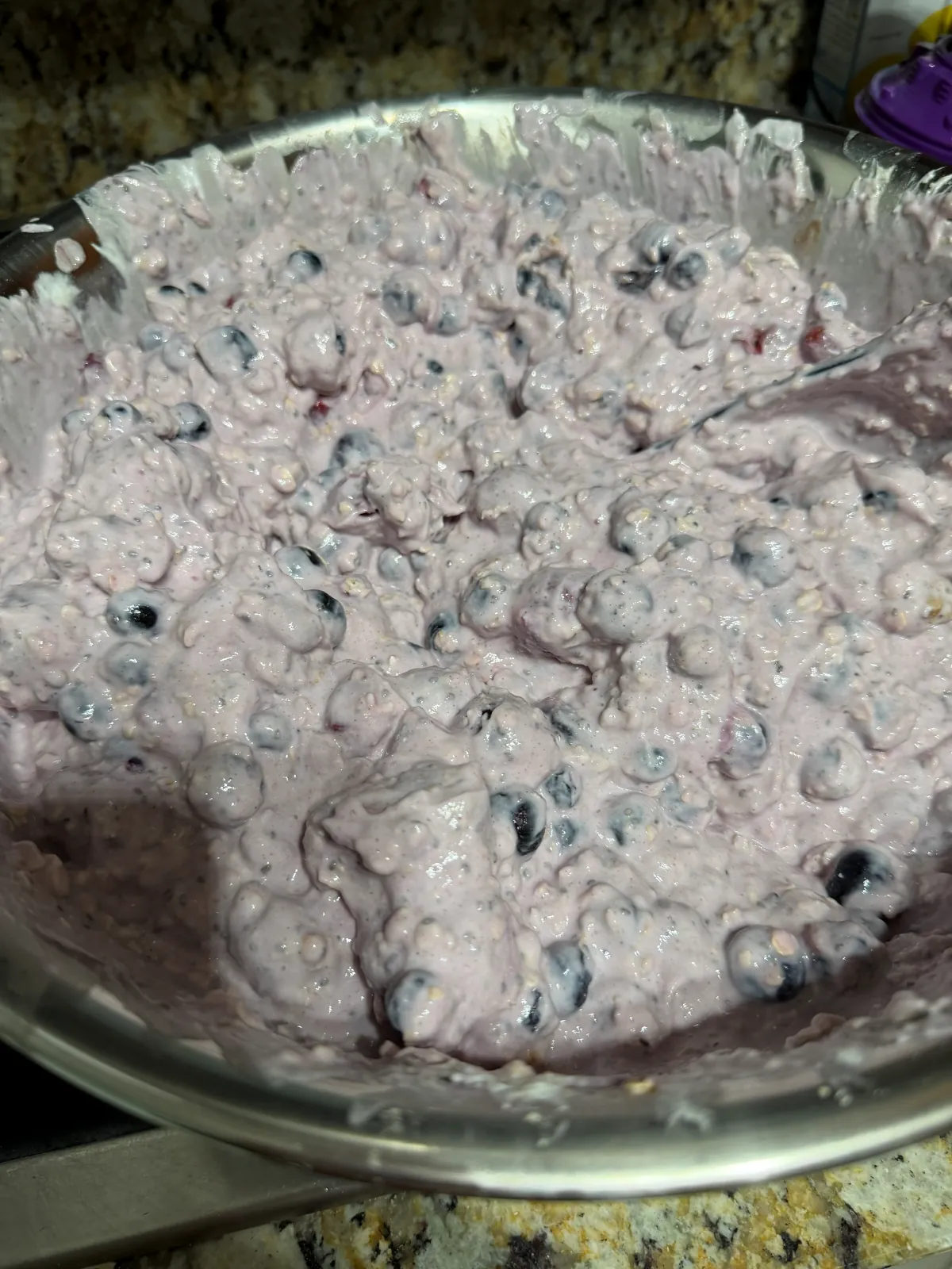 The same batch stirred together into a thick, lavender-colored gloop with whole blueberries showing